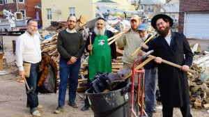 Baltimore team from Tiferes Yisroel Congregation including Yaakov Gur (second from left), Shlomo Goldberger (fourth from left) and Nossi Gross (fifth from left) help remove sand and debris from a flooded basement of a Seagate resident (in green apron).   