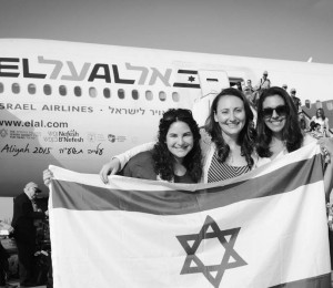 New olim hold up an Israeli flag on the tarmac at Ben Gurion Airport. Photo: Shahar Azran