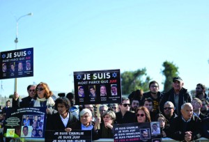 At the funeral of the four victims of the Paris kosher supermarket attack, mourners hold signs showing their solidarity with the victims of the Charlie Hebdo massacre in Paris. Photo: Israel Sun